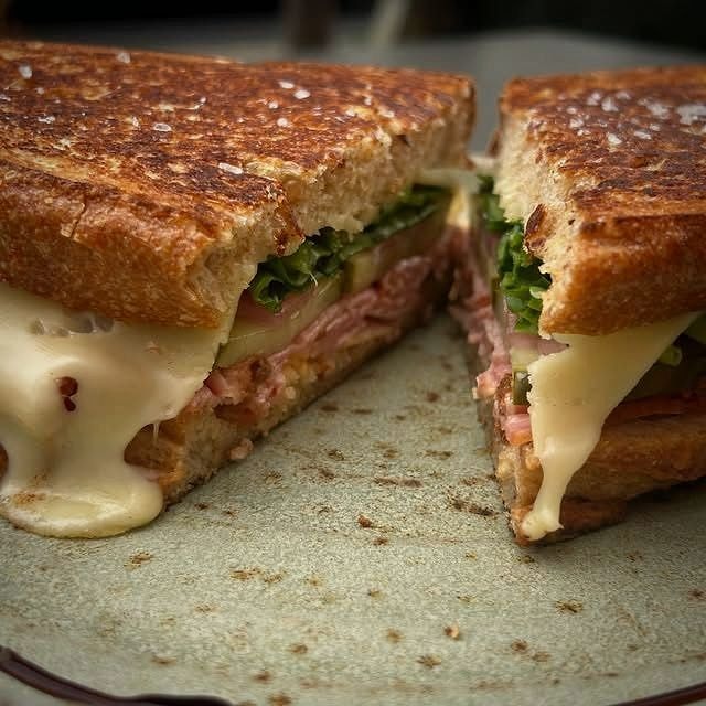 A gourmet ham and cheese toastie cut in half with the melt pulling apart